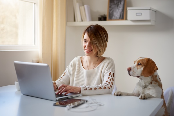 Woman browsing on her computer with her dog nearby